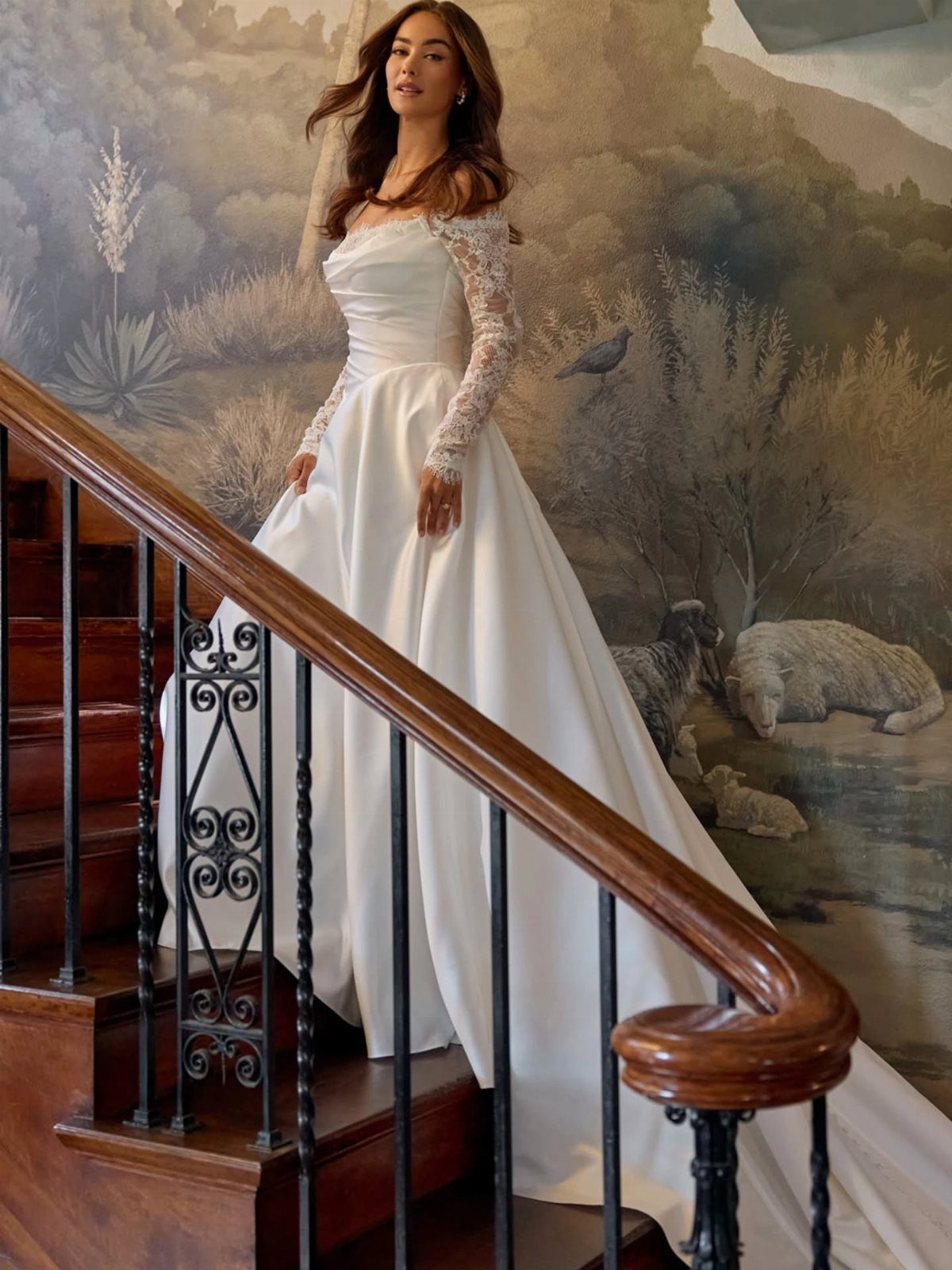 Woman wearing a white A-line wedding dress with lace sleeves standing on a wooden staircase.