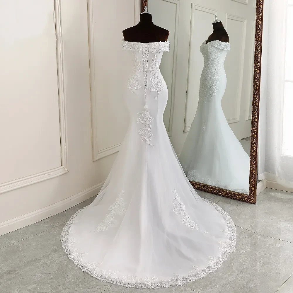 A white lace mermaid wedding dress on a mannequin with a long train.