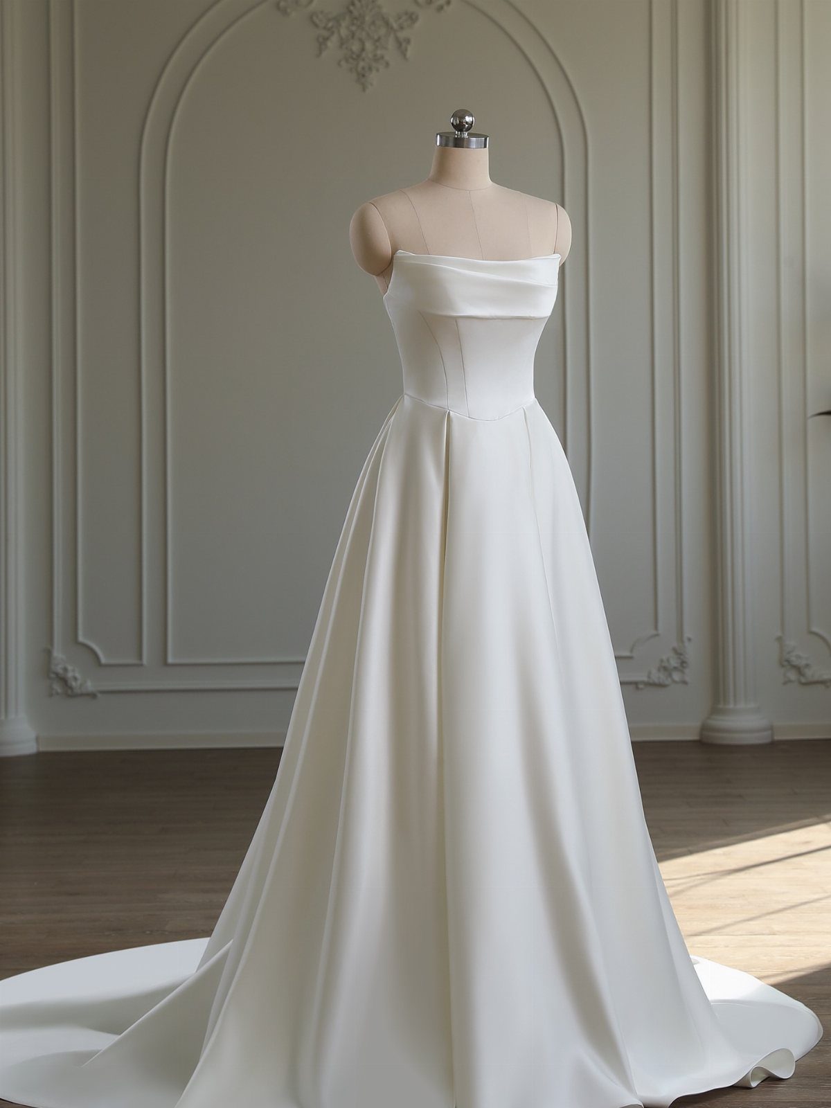 A white satin strapless wedding dress with princess seams displayed on a mannequin.